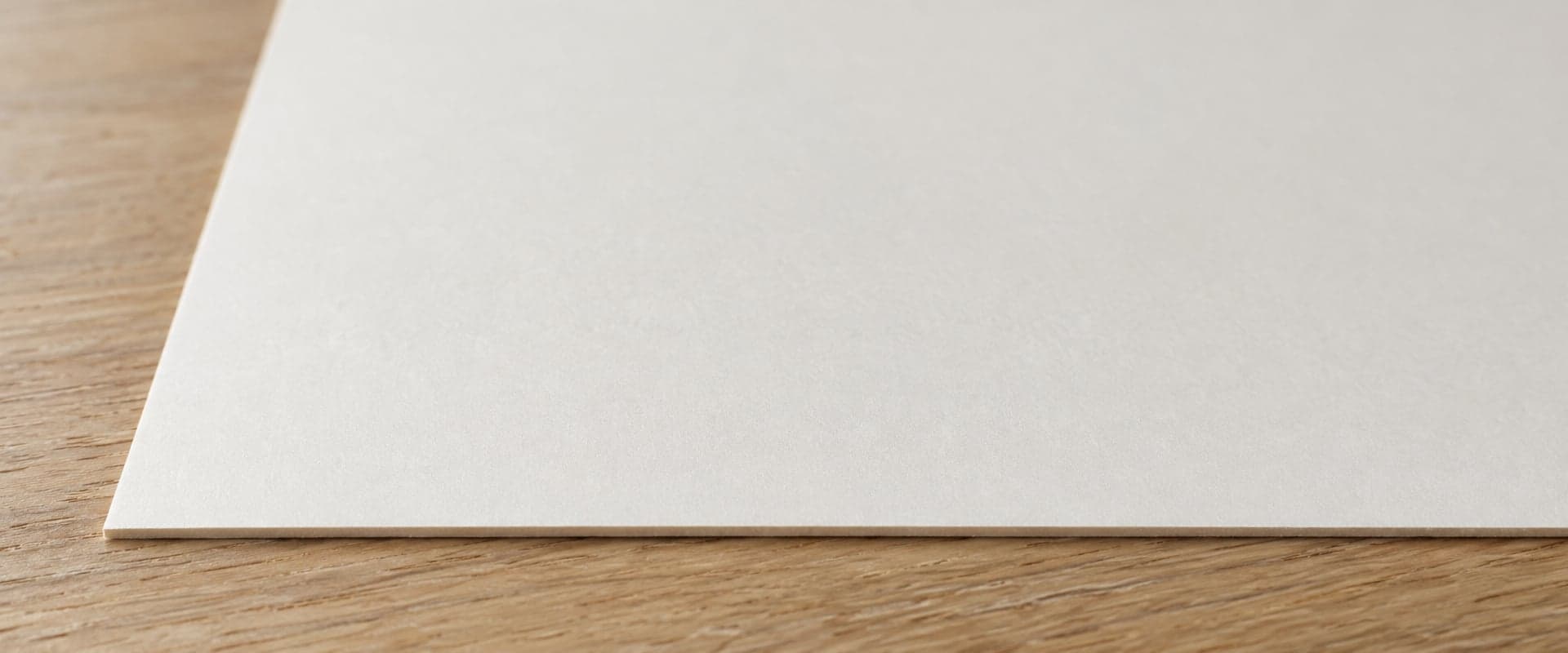 A sheet of smooth cotton fine art paper on an oak table, close up