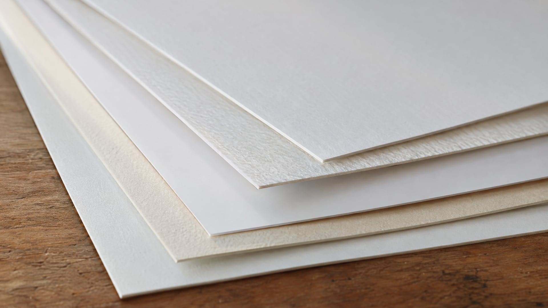 Sheets of fine art paper fanned out on a wooden table