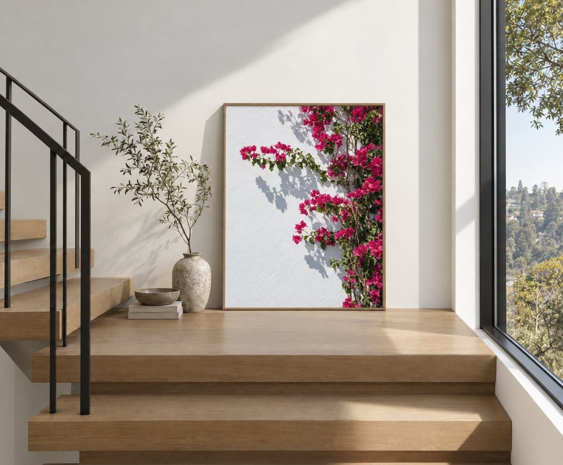 A large framed print of bougainvillea on a white wall, leaning on a stair landing
