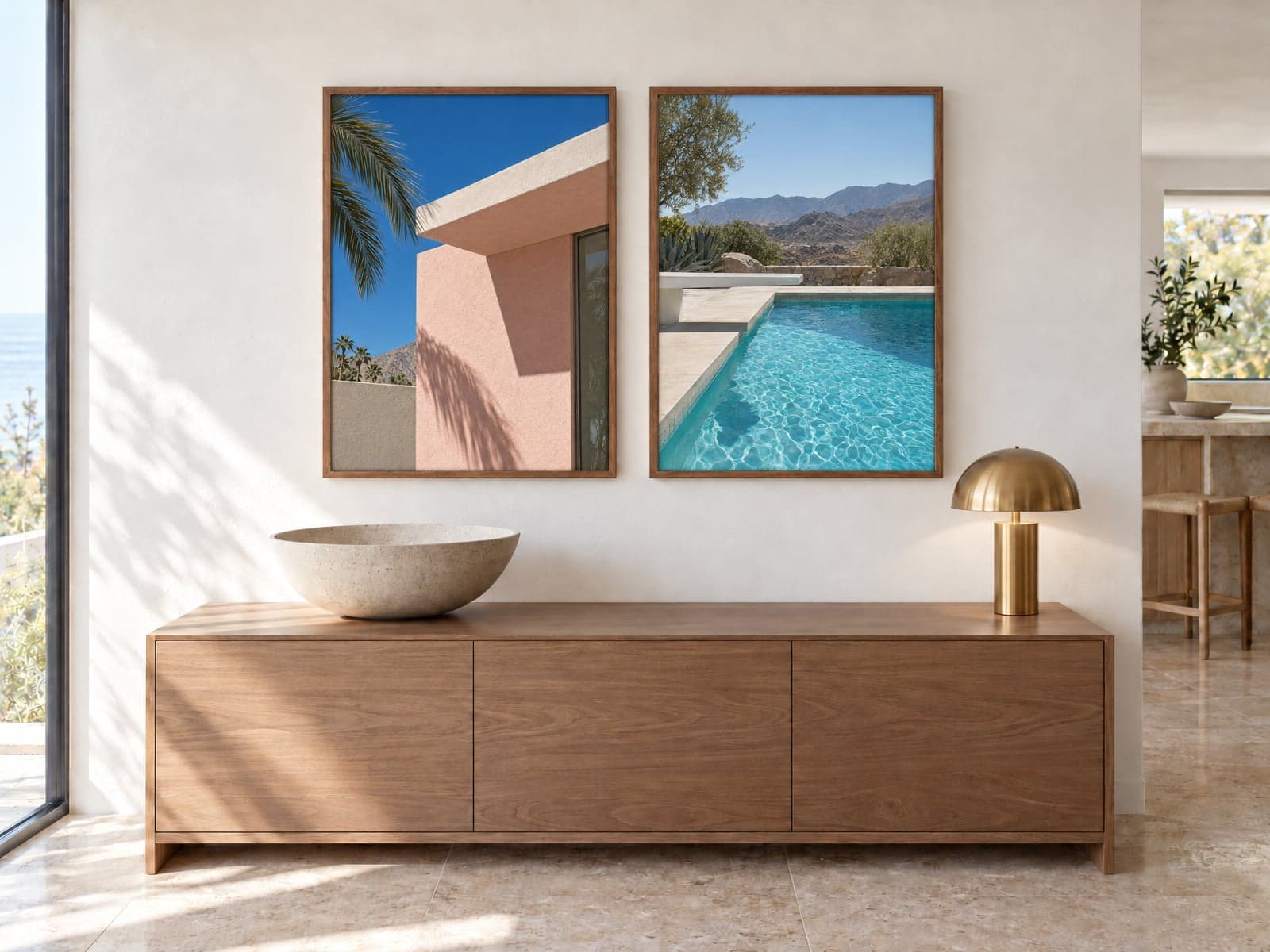 Two framed photos, a pink house with a palm and a swimming pool, above an oak sideboard
