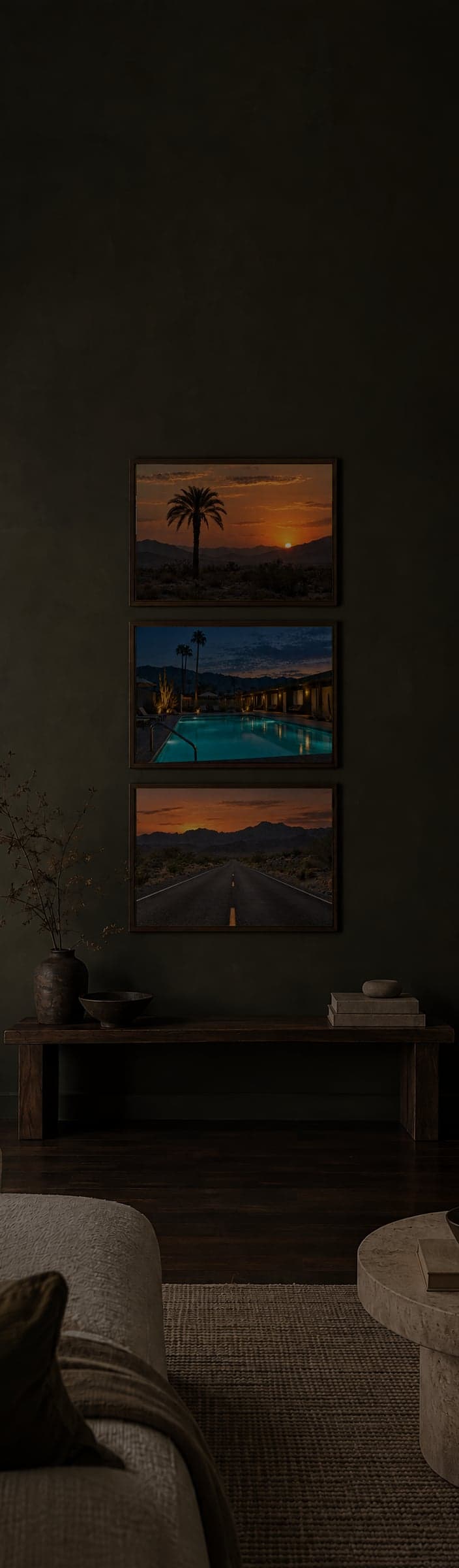 Framed color photos on a dark olive wall above a low wooden bench