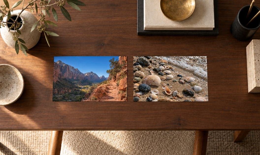 Two photo prints, a canyon trail and pebbles on a beach, on a walnut table